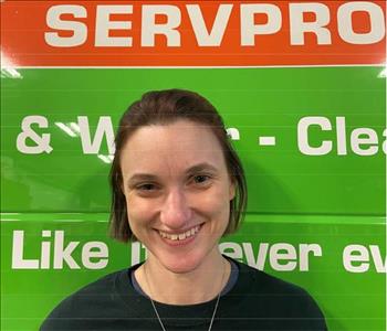 Woman with red hair standing in front of a Servpro vehicle